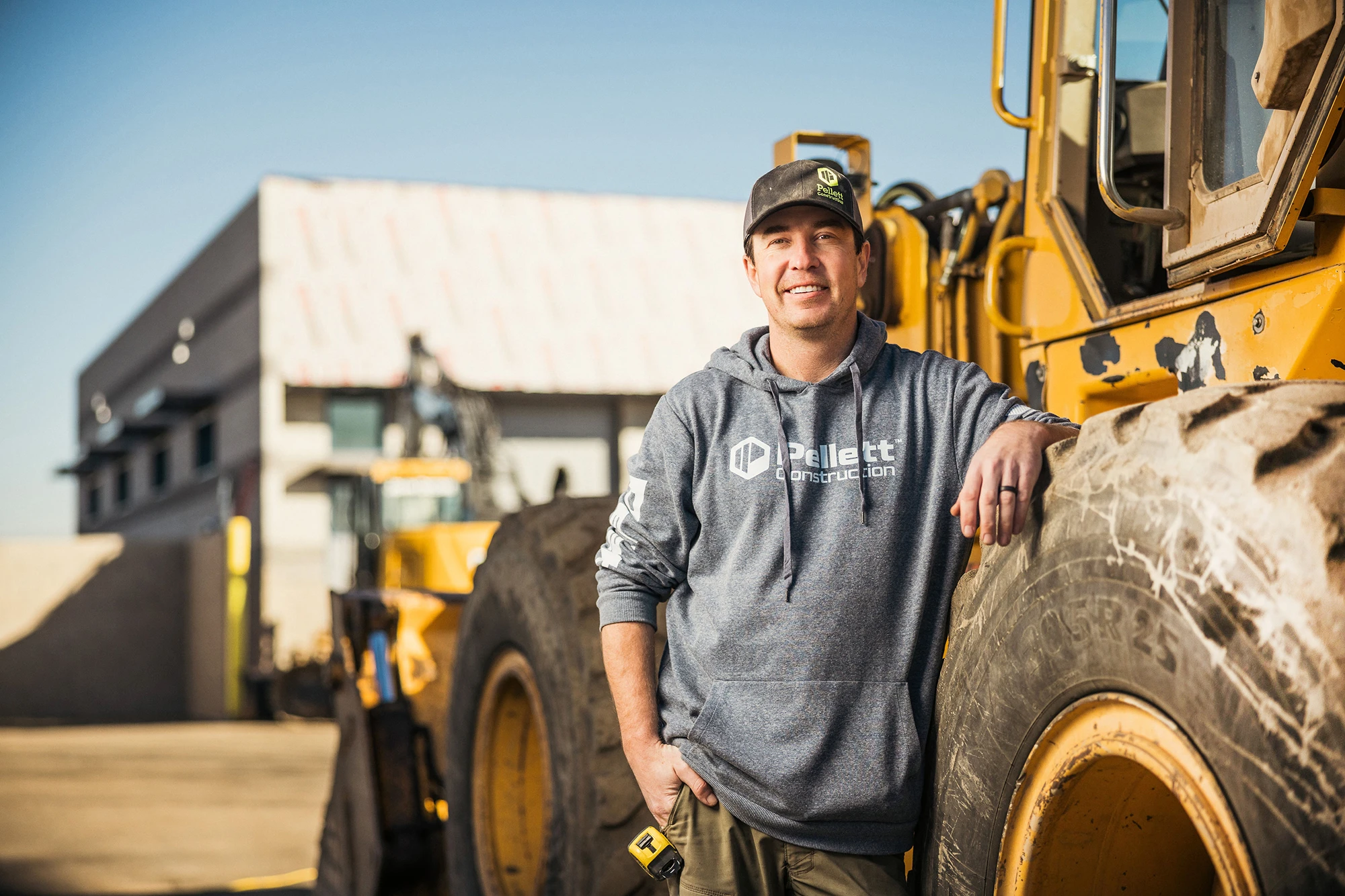 Pellett employee leaning against a tractor a jobsite